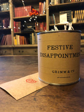 Load image into Gallery viewer, Image shows a tin of Festive Disappointment with kraft paper label, lid open to reveal wood wool shreds inside and mini kraft envelope stamped with a red 'G' monogram