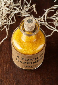Top view image of A Pinch of Happiness otherwise known as scented yellow bath salts in a glass bottle with cork