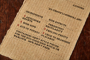 Image of close up kraft paper label of No More Newt with faux ingredients and side effects for humans.