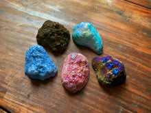 Load image into Gallery viewer, An image showing a collection of assorted colours of quartz geodes for the vacated genie geodes. These are shown upturned to show the rougher outside of the stone.