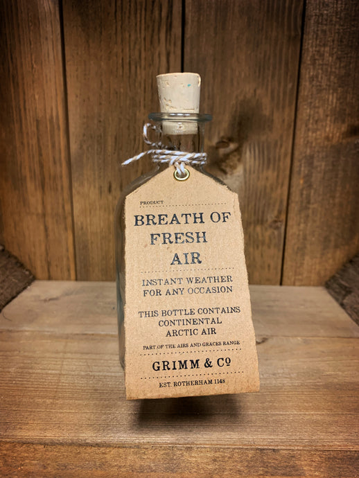 Image of the Breath of Fresh Air bottle from the Airs and Graces range: An empty glass potion bottle with cork. The bottle has a kraft tag around the neck, reading: Breath of Fresh Air. Instant weather for any occasion. This bottle contains continental arctic air.