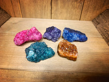 Load image into Gallery viewer, Image shows a side view of five pieces of Atlantean Sea Glass, showing the rock base as well as the crystal clusters. The colours are green, blue, pink, purple, and orange.