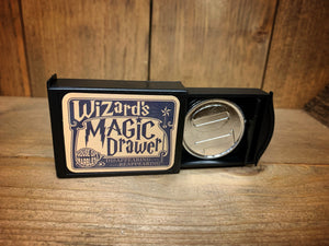 Image shows the Magic Draw opened with the silver coin inside. The switch that opens/closes the secret compartment is pushed up.