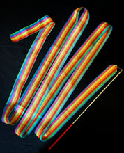 Load image into Gallery viewer, Image showing the Flying Colours ribbon wand laid out to form a zig-zag pattern. Ribbon is striped in blue, pink, yellow, orange, red, green and blue. Wand is white with a red handle.