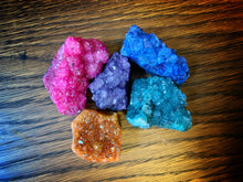 Load image into Gallery viewer, Image shows a downward view of five pieces of Atlantean Sea Glass (colour-dyed quartz clusters).  The colours are green, blue, purple, pink, and orange.