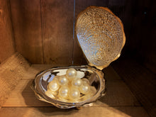 Load image into Gallery viewer, Image shows a small pile of cream-coloured bath pearls sitting inside a silver clam shell.