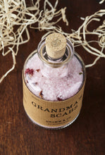 Load image into Gallery viewer, Top view of Grandma&#39;s Scabs potion bottle, a glass bottle and cork of pale pink bath salts and dried rose petals.