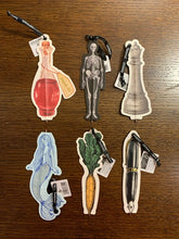 Load image into Gallery viewer, Image shows 6 flat paper pens with various shapes and illustrated designs including a potion bottle saying drink me, a skeleton, a chess piece, a silver foiled mermaid, a carrot with leafy top and a fountain pen with gold foil.