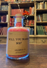 Load image into Gallery viewer, Image of a glass potion bottle filled with red bath salts. The bottle label reads: Will You Marry Me?