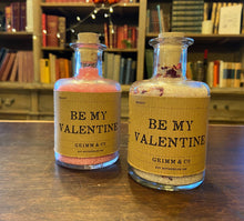 Load image into Gallery viewer, Image of two glass potion bottles filled with pink bath salts, one including rose petals. Both are labeled: Be My Valentine.