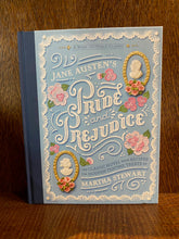 Load image into Gallery viewer, Image shows the front cover of the book Pride &amp; Prejudice - A Book to Table Classic. The cover is pastel blue with a navy blue linen spine. There are illustrations of cameos of MR. Darcey and Elizabeth Bennett and icing sugar flowers decorating the cover. The text is white.