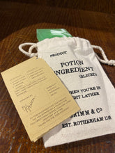 Load image into Gallery viewer, Image shows a white linen drawstring pouch with a Luck of the Irish soap slice poking out the top, and a kraft label showing the faux ingredients and side effects.