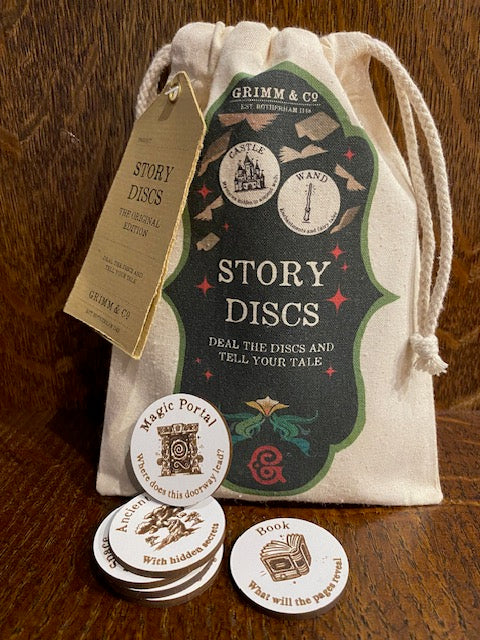 Image shows a cotton printed pouch with the text 'Story Discs' with some of the MDF printed discs stacked in front depicting a Magic Portal, Book and an Ancient Forest.