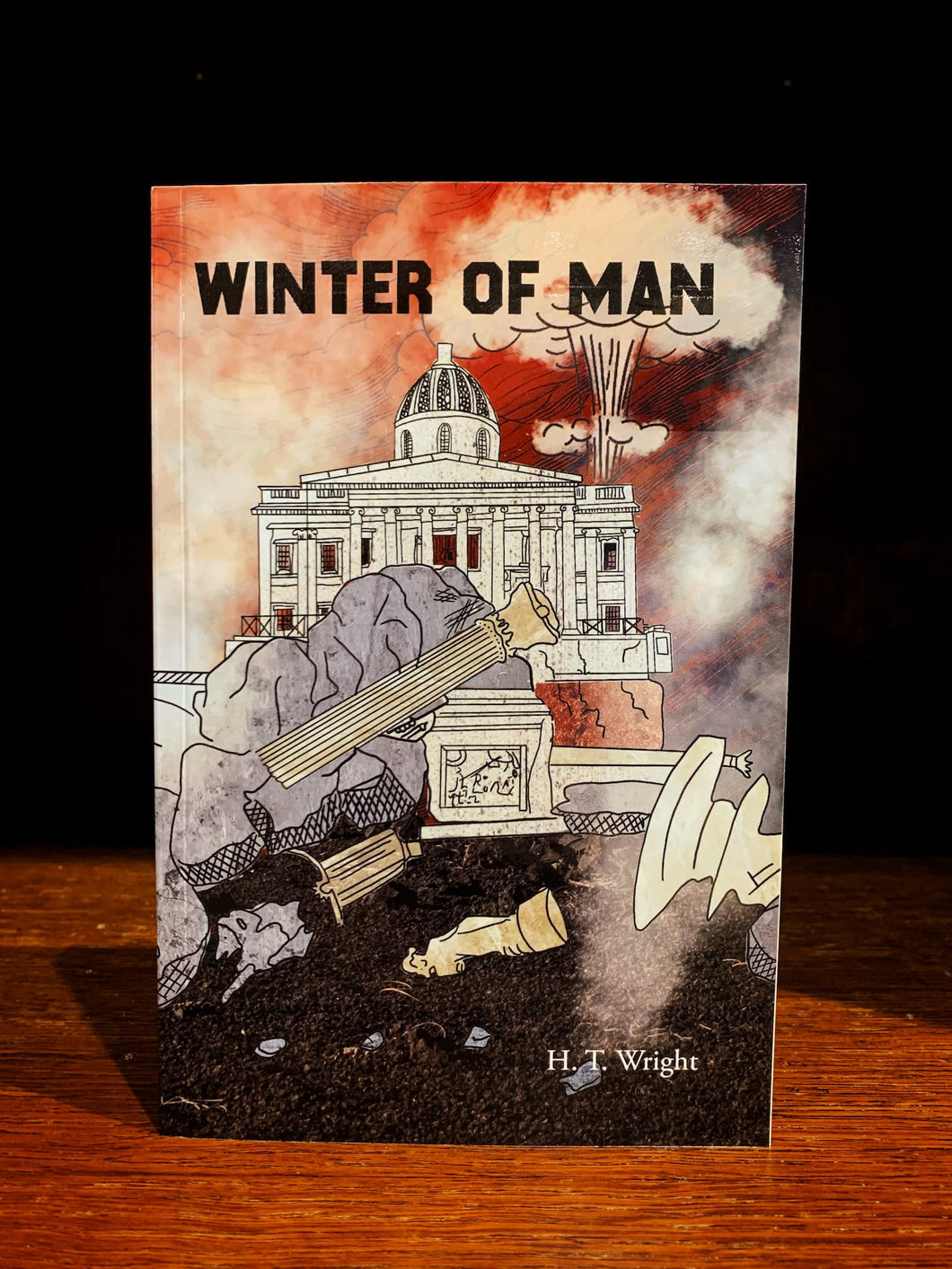 Book cover of 'Winter of Man' by H.T. Wright with a dramatic illustration on a wooden surface.
The illustration shoes ruins of London, with rubble and St. Pauls in ruins in the foreground, and a nuclear mushroom blast in the background. The sky is red, and black, with white smoke. 