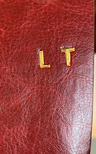 Image shows the initials LT embossed onto a burgundy journal using gold foil.