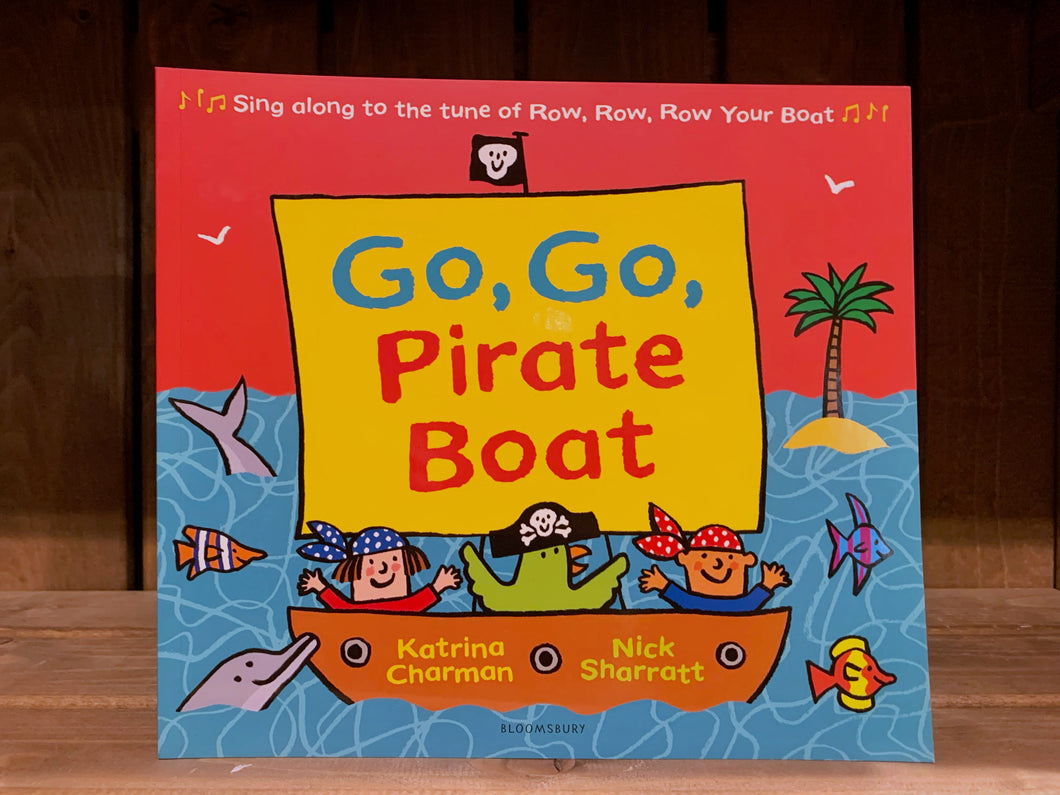 Image of the front cover of Go, Go Pirate Boat. the cover has a red background, with an illustration of a ship sailing on the sea. The boat has two people and a parrot in it, all wearing pirate hats and bandanas, there are fish and dolphins in the surrounding sea, and a small island and palm tree in the background.