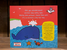 Load image into Gallery viewer, Image of the back cover of Go, Go Pirate Boat. The background is still red, and the illustration of the sea continues, this time with a whale, a crab, and a starfish, and there is a cliff in the background.