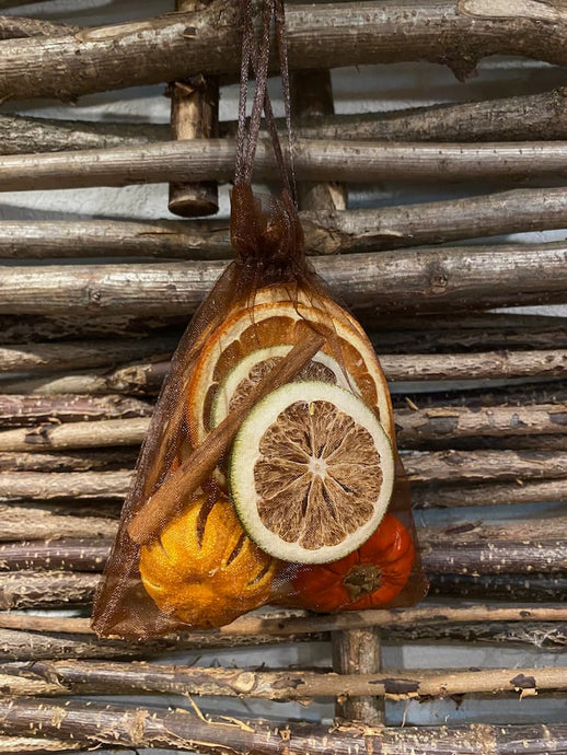 Image of the small brown organza fabric bag of pot pourri including cinnamon sticks, dried whole oranges, dried orange and green orange slices and a dried mini pumpkin