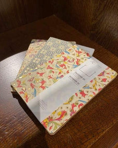 Image shows a selection of three patterned A5 notebooks with different designs, featuring colours including red, green, purple, orange and blue on an ivory background with gold powder finish. Designs vary including geometric tile patterns and floral patterns.