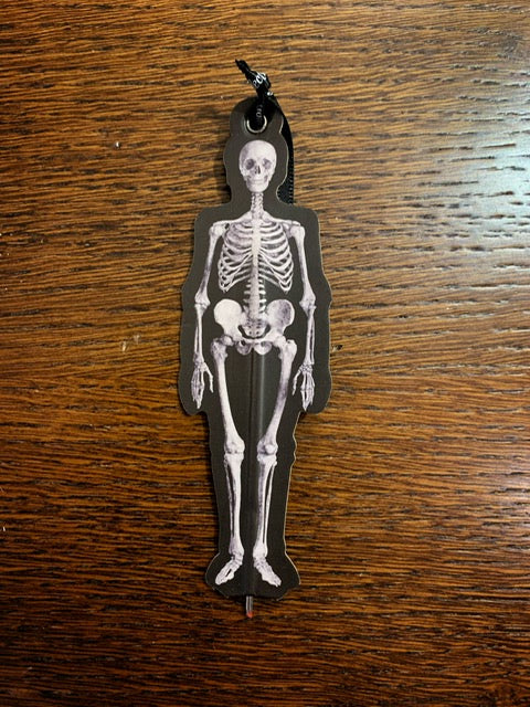 Image shows an illustrated flat paper pen shaped like a skeleton with a black background.