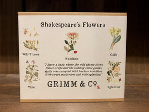 Image shows the box for the Shakespeare's Flowers seed collection. The box is a small, flat, rectangular 5 x 4 inch box made of kraft card, and has a white label folded over and underneath. The label has 'Shakespeare's Flowers' printed at the top, 5 illustrations of the flowers/herbs contained within, with both common and scientific names listed underneath,, and an extract from A Midsummer Night's Dream which contains all the flowers/herbs listed. The Grimm & Co. logo is printed at the bottom. 