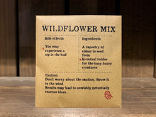 Load image into Gallery viewer, Image shows a packet of Wildflower Mix seeds. It is a square, flat, kraft brown paper packet., with black text printed in Appareo font. It says Wildflower Mix at the top, with magical ingredients and side effects underneath, and a magical &#39;caution&#39; at the bottom. 