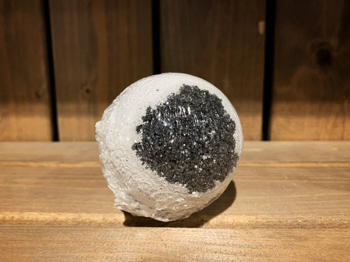 Image shows a single Spare Eye bath bomb. It is round and white, with a black charcoal centre - resembling a large eyeball.