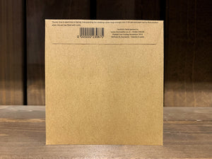 Image shows the back of a seed packet. It is made of kraft brown paper, and is sealed shut with a folded flap. At the top of the flap there are instructions written in small font. 