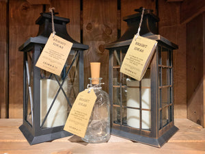 Image shows the full Bright Ideas collection featuring the Bottle and Lantern styles. Image shows a black and bronze coloured plastic lantern with the glass bottle Bright Ideas in the front. Lanterns contain a battery operated candle, bottle contains LED battery operated string lights inside.