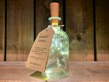Load image into Gallery viewer,  Image showing Bright Ideas Bottle - a glass bottle with LED string lights inside attached to a cork style stopper. Lights are warm toned.