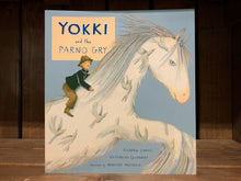 Load image into Gallery viewer, image of the front cover of Yokki and the Parno Gry. The background is a pale blue colour, and there is an illustration of a white horse covered in grey birds with a boy riding on its back.