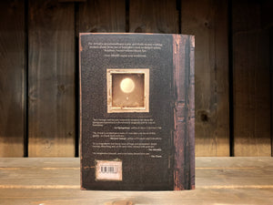 Image shows the back cover of The Arrival. the distressed old leather book theme continues, and there is an illustration of a small square sepia photograph. the photograph shows a glowing balloon with a small container hanging underneath. 