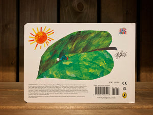 Image of the back of The Very Hungry Caterpillar. It has a white background and an illustration of a  green leaf with a tiny caterpillar crawling on it from an egg, and the sun is in the background. 