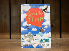 Load image into Gallery viewer, image of the front cover of Rumblestar. The cover has an illustration of a red hot air balloon with two silhouetted passengers. One is falling out of the balloon basket, with the other holding onto them. the background is bright blue sky with white clouds, and underneath a mountain and forest skyline with a castle to one side. the title &#39;Rumblestar&#39; is written in gold lettering on the red balloon.