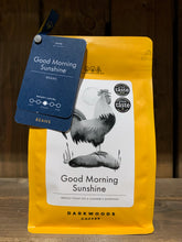 Load image into Gallery viewer, Image of the Roasted Magic Beans (Whole) - Good Morning Sunshine coffee beans. The image shows a bright yellow packet with a black and white drawing of a rooster. There are two labels attached to the top left corner of the packet with the name of the coffee, the fact that it is decaf, and the label underneath states that they are beans.