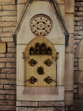 Load image into Gallery viewer, Image shows a special Grimm edition fairy door stuck onto a decorative stone background. All door accessories are also cut out and stuck on - window frames, decorative hinges, and the center Grimm insignia.