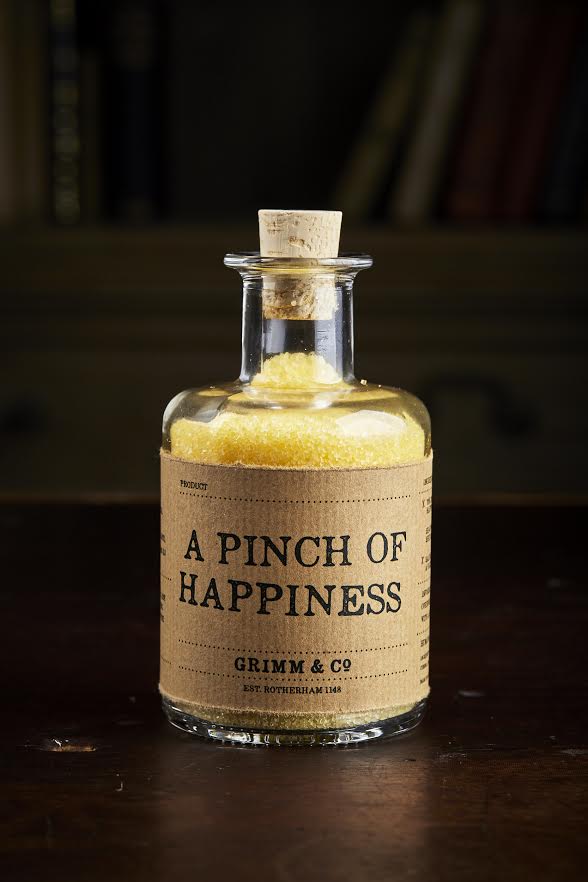 Image of A Pinch of Happiness otherwise known as scented yellow bath salts in a glass bottle with cork 