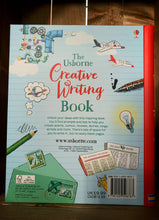 Load image into Gallery viewer, Image of the back of The Creative Writing Book. The back has a pale blue, lined background, with a red spine. There are more illustrations related to forms of writing and creativity, including a letter and stamps, a glowing lightbulb, and more newspapers. Information about the book is written in the center in black text.