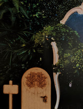 Load image into Gallery viewer, Image shows an arch edition fairy door stuck onto a background of plant life, next to a giant chair. Door handle and standing sign accessories are also included.