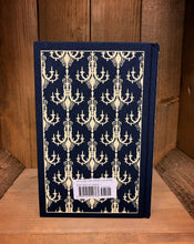 Load image into Gallery viewer, Image of the back cover of the Penguin clothbound classic Great Expectations, featuring a navy blue background and a repeat pattern of cream coloured chandeliers.