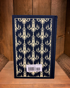 Image of the back cover of the Penguin clothbound classic Great Expectations, featuring a navy blue background and a repeat pattern of cream coloured chandeliers.