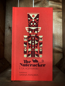 Image showing the front cover of The Nutcracker. The cover is clothbound and red, featuring an illustration of the traditional nutcracker soldier by Sanna Annukka.