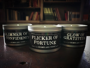 Image of full range of candles in tins showing Glimmer of Confidence, Flicker of Fortune and Glow of Gratitude