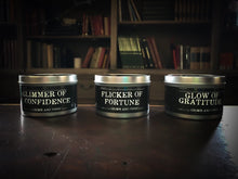 Load image into Gallery viewer, Image showing all three tinned candles in the Grimm &amp; Tonic range including Glimmer of Confidence, Flicker of Fortune and Glow of Gratitude. Candles in silver tins with black labels and white text