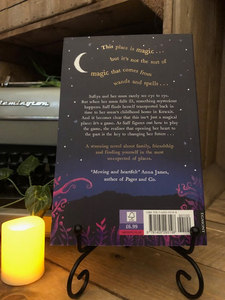 Image of the back cover of the paperback book A Pocketful of Stars stood on a book stand with candles