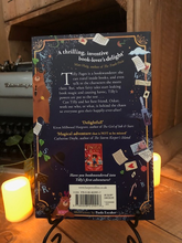 Load image into Gallery viewer, Image of the back of the paperback book Pages &amp; Co: Tilly and the Lost Fairy Tales written by Anna James and illustrated by Paola Escobar. Displayed on a book stand with candles.