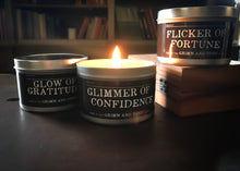 Load image into Gallery viewer, Image of lit candle in a tin, with two other candles in tins with lids shown either side