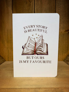 Image shows the front of the Beautiful Story Card. It features an illustration of a half open book and floating stars in rusty browns and reds,  with 'Every story is beautiful' written above, and 'But ours is my favourite' written underneath. The card design is printed onto a pearlescent  white card.