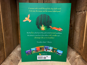 Image shows the back cover of the book The Gruffalo. The cover is plain forest green, with a blurb in yellow and white text, and a small illustration of the Mouse walking through the woods, with an owl and a fox on either side. 