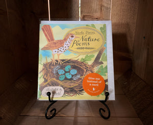 Image of the front of the book/card Nature Poems. The cover shows an illustration of a bird standing on the edge of a nest filled with blue eggs, in front of a blue sky.  It is displayed on a book stand.